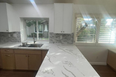 Large l-shaped vinyl floor and multicolored floor eat-in kitchen photo in San Francisco with a double-bowl sink, flat-panel cabinets, light wood cabinets, quartzite countertops, multicolored backsplash, glass tile backsplash, stainless steel appliances, an island and multicolored countertops