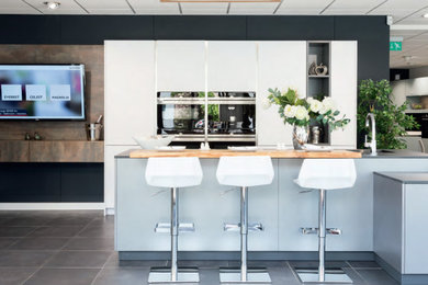 Offene, Einzeilige, Mittelgroße Moderne Küche mit flächenbündigen Schrankfronten, weißen Schränken, Laminat-Arbeitsplatte, Kücheninsel und grauer Arbeitsplatte in London