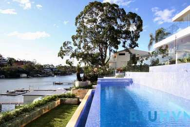 Large front yard custom-shaped lap pool in Sydney with a hot tub and tile.