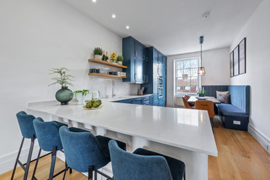 This is an example of a large contemporary kitchen/dining room in London with white walls and feature lighting.
