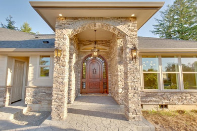 Example of a classic beige one-story stone house exterior design in Portland with a hip roof and a shingle roof