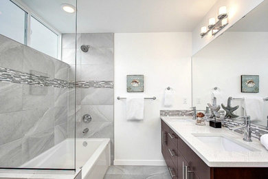 This is an example of a mid-sized contemporary master bathroom in Newark with flat-panel cabinets, medium wood cabinets, an alcove tub, a shower/bathtub combo, stone tile, white walls, marble floors, an undermount sink and engineered quartz benchtops.