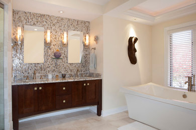 Freestanding bathtub - mid-sized contemporary master beige tile, brown tile, gray tile, multicolored tile, white tile and mosaic tile limestone floor freestanding bathtub idea in Cleveland with shaker cabinets, dark wood cabinets, beige walls, an undermount sink and granite countertops
