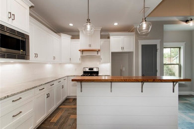 Open concept kitchen - large craftsman l-shaped dark wood floor and brown floor open concept kitchen idea in Miami with an undermount sink, shaker cabinets, white cabinets, marble countertops, white backsplash, subway tile backsplash, stainless steel appliances and an island