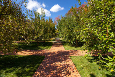 This is an example of a large transitional backyard partial sun formal garden for fall in New York with a garden path and brick pavers.