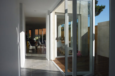 Photo of a mid-sized contemporary hallway in Sydney with white walls, ceramic floors and grey floor.