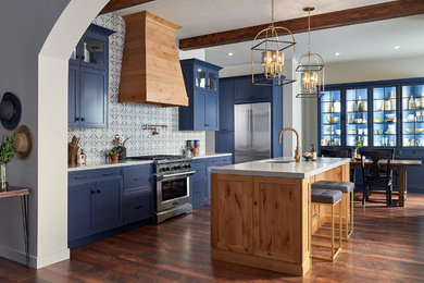This is an example of a large beach style l-shaped eat-in kitchen in San Diego with an undermount sink, shaker cabinets, blue cabinets, solid surface benchtops, blue splashback, porcelain splashback, stainless steel appliances, with island, brown floor, grey benchtop and dark hardwood floors.