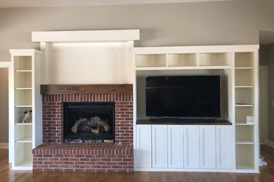 Inspiration for a large transitional open concept medium tone wood floor and brown floor family room remodel in Omaha with beige walls, a standard fireplace, a brick fireplace and a media wall