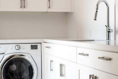 This is an example of a laundry room in Other with white cabinets and white benchtop.