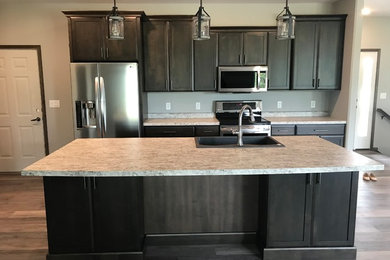 Open concept kitchen - large transitional galley open concept kitchen idea in Cedar Rapids with a double-bowl sink, shaker cabinets, dark wood cabinets, laminate countertops, stainless steel appliances, an island and gray countertops