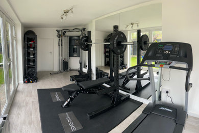 Small contemporary home gym in Sussex with laminate floors and grey floor.