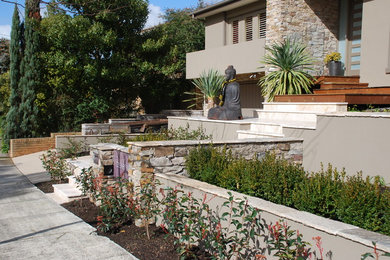 Mid-sized contemporary front yard full sun formal garden in Melbourne with natural stone pavers and a stone fence for spring.