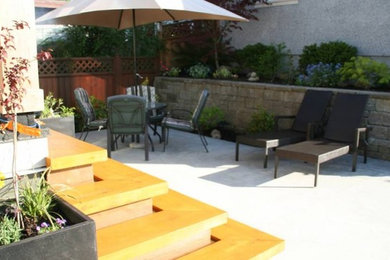 Example of a backyard stone patio container garden design in Vancouver with a roof extension