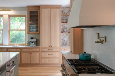 Inspiration for a large transitional u-shaped light wood floor and brown floor open concept kitchen remodel in DC Metro with an undermount sink, flat-panel cabinets, light wood cabinets, quartz countertops, white backsplash, quartz backsplash, paneled appliances, an island and white countertops