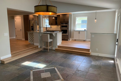 Arts and crafts l-shaped eat-in kitchen photo in Denver with a farmhouse sink, shaker cabinets, quartzite countertops, ceramic backsplash, stainless steel appliances and an island