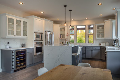 Example of a large arts and crafts u-shaped dark wood floor open concept kitchen design in Portland with an undermount sink, shaker cabinets, gray cabinets, quartz countertops, white backsplash, stone slab backsplash, stainless steel appliances and an island