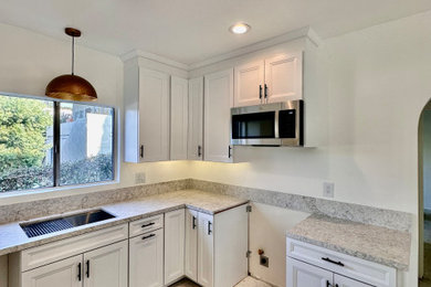 Eat-in kitchen - modern eat-in kitchen idea in Los Angeles with an undermount sink, shaker cabinets, white cabinets, solid surface countertops, gray backsplash, stone slab backsplash and gray countertops