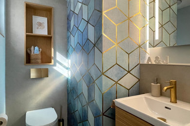 Kleine Moderne Gästetoilette mit flächenbündigen Schrankfronten, hellen Holzschränken, Wandtoilette, beigen Fliesen, Keramikfliesen, blauer Wandfarbe, Keramikboden, Aufsatzwaschbecken, beigem Boden und schwebendem Waschtisch in Köln