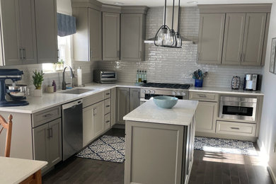 Photo of a transitional l-shaped eat-in kitchen in Philadelphia with shaker cabinets, grey cabinets, quartz benchtops, stainless steel appliances, with island and white benchtop.