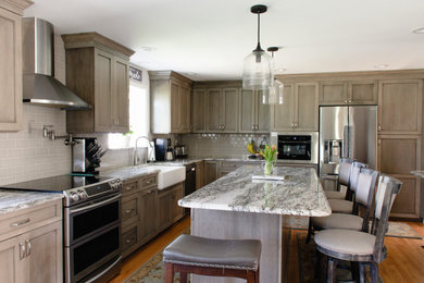 Large farmhouse l-shaped medium tone wood floor and red floor eat-in kitchen photo in Providence with a farmhouse sink, recessed-panel cabinets, medium tone wood cabinets, granite countertops, beige backsplash, ceramic backsplash, stainless steel appliances, an island and gray countertops