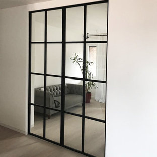 This is an example of a large modern home office and library in Milan with white walls, laminate floors and grey floors.