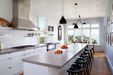 This is an example of a contemporary galley eat-in kitchen in San Francisco with an undermount sink, quartz benchtops, white splashback, stainless steel appliances, medium hardwood floors, with island and flat-panel cabinets.