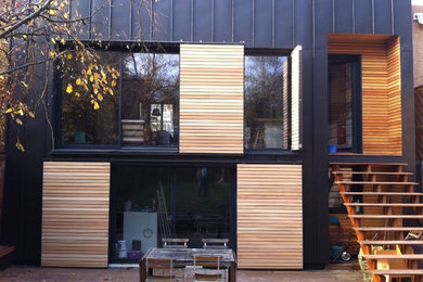 Inspiration for a modern three-storey black house exterior in Paris with wood siding.