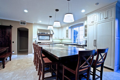 Large elegant l-shaped travertine floor and beige floor open concept kitchen photo in Orange County with an undermount sink, recessed-panel cabinets, white cabinets, granite countertops, white backsplash, subway tile backsplash, paneled appliances and an island