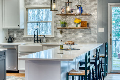 Inspiration for a large modern u-shaped light wood floor and brown floor open concept kitchen remodel in Baltimore with a farmhouse sink, shaker cabinets, blue cabinets, quartz countertops, multicolored backsplash, ceramic backsplash, stainless steel appliances, two islands and white countertops