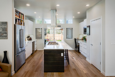 This is an example of a mid-sized transitional separate kitchen in Seattle with an undermount sink, flat-panel cabinets, white cabinets, quartz benchtops, white splashback, subway tile splashback, stainless steel appliances, light hardwood floors, with island and beige floor.