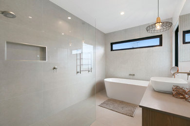 This is an example of a mid-sized contemporary bathroom in Melbourne with light wood cabinets, a freestanding tub, an open shower, gray tile, stone tile, grey walls, porcelain floors, engineered quartz benchtops, grey floor, an open shower and grey benchtops.