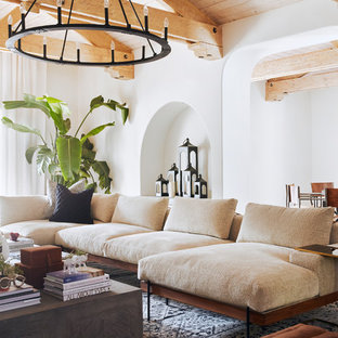 Design ideas for a large mediterranean open plan family and games room in Phoenix with brown walls, slate flooring, a standard fireplace, a concrete fireplace surround, a wall mounted tv and brown floors.