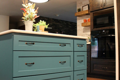 Example of a mid-sized mountain style l-shaped medium tone wood floor and brown floor open concept kitchen design in Milwaukee with a farmhouse sink, shaker cabinets, dark wood cabinets, quartzite countertops, beige backsplash, ceramic backsplash, black appliances, an island and beige countertops