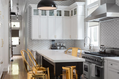 Transitional l-shaped medium tone wood floor kitchen photo in San Francisco with an undermount sink, recessed-panel cabinets, multicolored backsplash, stainless steel appliances and an island