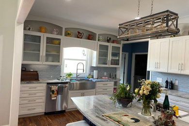 Inspiration for a large transitional u-shaped medium tone wood floor open concept kitchen remodel in Atlanta with a farmhouse sink, beaded inset cabinets, white cabinets, quartz countertops, blue backsplash, subway tile backsplash, stainless steel appliances and an island