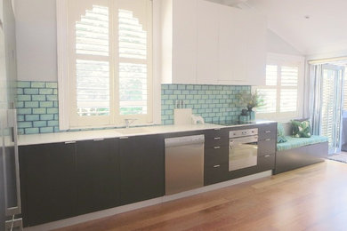 Photo of a large contemporary l-shaped eat-in kitchen in Sydney with an integrated sink, blue splashback, no island and solid surface benchtops.