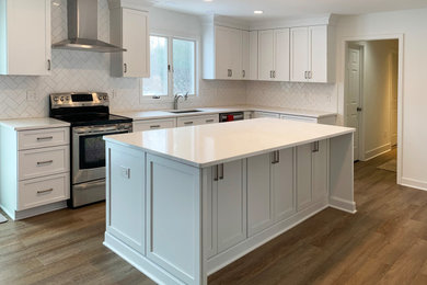 This is an example of a traditional kitchen/diner in Cleveland with a submerged sink, shaker cabinets, white cabinets, white splashback, stainless steel appliances, an island and white worktops.