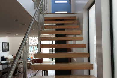 Example of a large minimalist wooden floating metal railing staircase design in Other with wooden risers