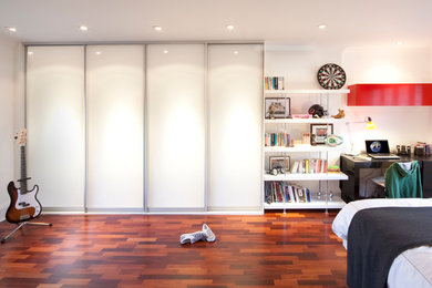 Photo of a mid-sized contemporary kids' room for boys in London with white walls, dark hardwood floors and brown floor.