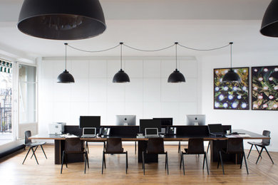 Diseño de despacho moderno grande con paredes blancas, suelo de madera en tonos medios y suelo marrón