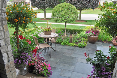 Small contemporary front yard patio in Chicago with a container garden, natural stone pavers and a roof extension.