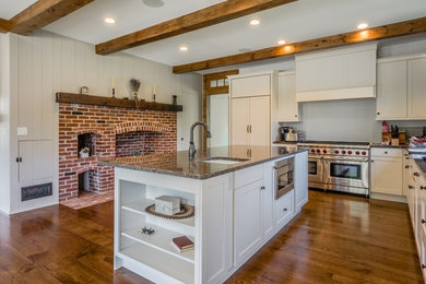 Large elegant dark wood floor and brown floor kitchen photo in Boston with a farmhouse sink, white cabinets, stainless steel appliances and an island