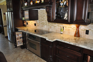 Inspiration for a large timeless u-shaped travertine floor eat-in kitchen remodel in Miami with an undermount sink, raised-panel cabinets, dark wood cabinets, granite countertops, multicolored backsplash, matchstick tile backsplash, stainless steel appliances and an island