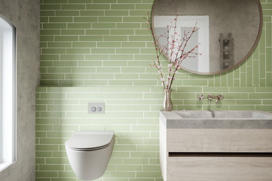 Inspiration for a medium sized contemporary ensuite bathroom in Surrey with flat-panel cabinets, light wood cabinets, a built-in bath, a shower/bath combination, a wall mounted toilet, green tiles, ceramic tiles, grey walls, ceramic flooring, a built-in sink, concrete worktops, white floors, an open shower, grey worktops, a single sink, a floating vanity unit and wallpapered walls.