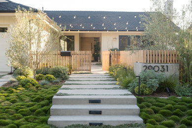 Photo of a contemporary drought-tolerant front yard concrete paver and wood fence landscaping in Orange County with a fire pit.