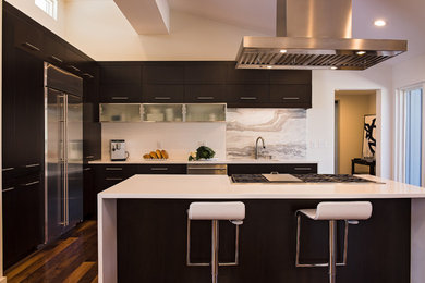 Large trendy u-shaped dark wood floor open concept kitchen photo in Phoenix with a drop-in sink, dark wood cabinets, laminate countertops, white backsplash, stone slab backsplash, stainless steel appliances, an island and flat-panel cabinets