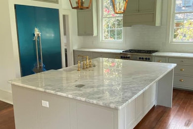 Example of a medium tone wood floor kitchen design in Charleston with a farmhouse sink, gray cabinets, quartz countertops, white backsplash, subway tile backsplash, stainless steel appliances, an island and white countertops