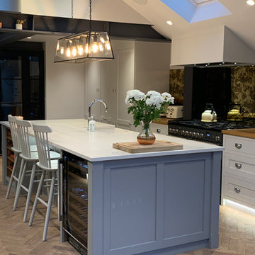 Light grey kitchen with large island and integrated sink and wine fridge