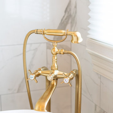 Freestanding Tub with Wall-Mounted Gold Filler and Marble Surround