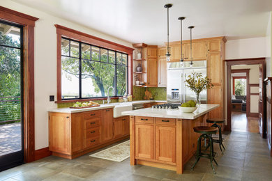 Design ideas for an arts and crafts l-shaped eat-in kitchen in Los Angeles with a farmhouse sink, shaker cabinets, medium wood cabinets, green splashback, stainless steel appliances and with island.